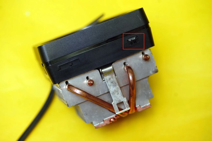 A side view of the stock AMD Wraith Prism CPU cooler against a yellow background.