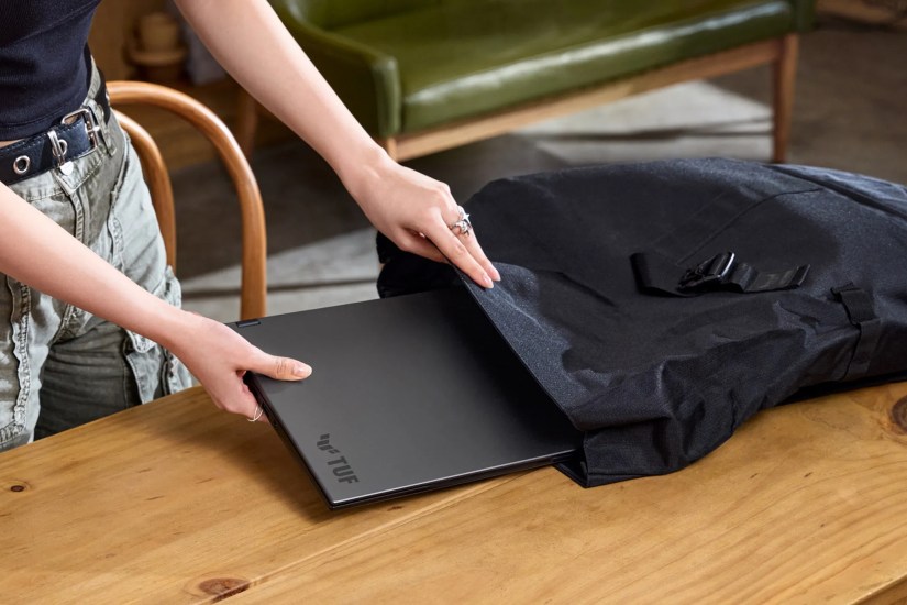 A person taking a black laptop out of a black bag.