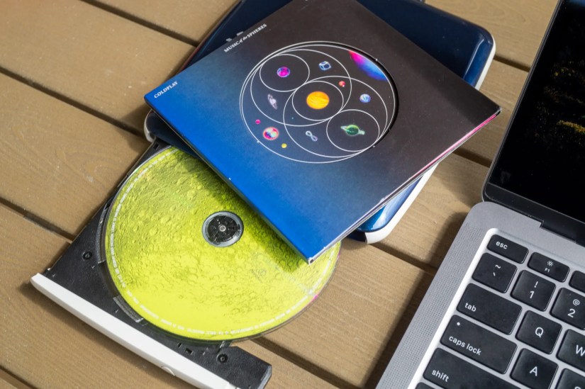 CD drive and a music CD next to a MacBook Air.