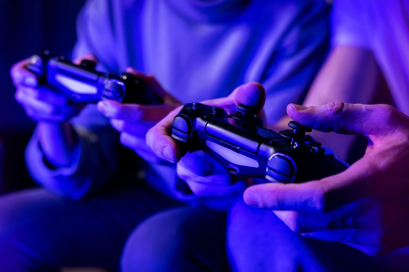 Two friends playing a multiplayer game on the sofa each with a controller in hand.