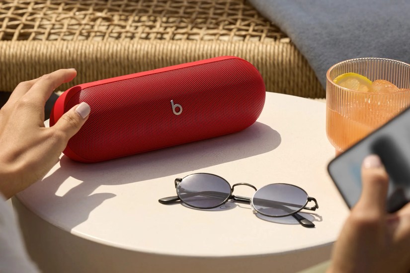 The 2024 Beats Pill on a table with a drink and some sunglasses.