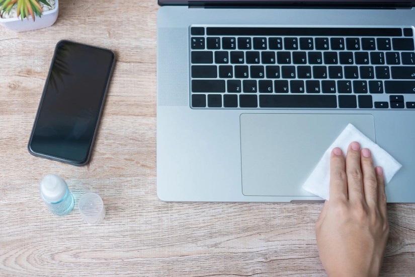 Woman&rsquo;s hand cleaning laptop and smartphone by wet wipes tissue and alcohol disinfectant.