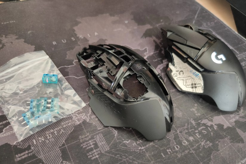 The Logitech G502 Lightspeed next to a replacement mouse shell and some microswitches.