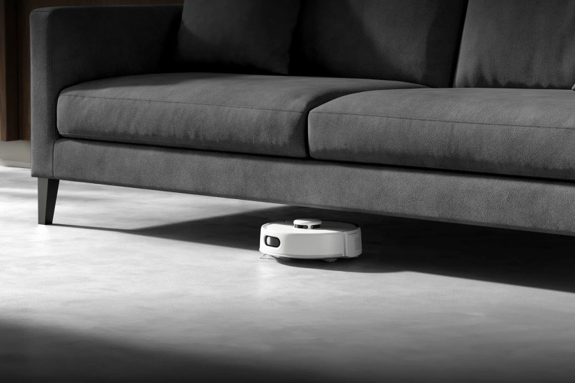 The tiny SwitchBot K10+ Pro robot vacuum under a sofa.