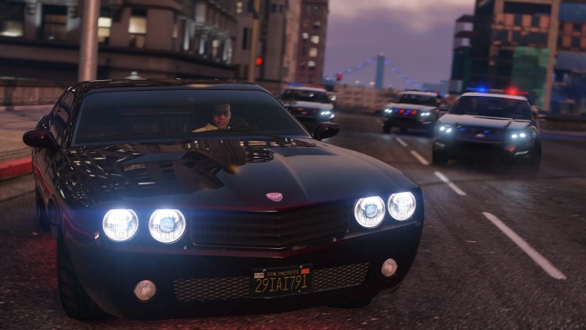 A promotional screenshot from GTA V showing a police car chase.