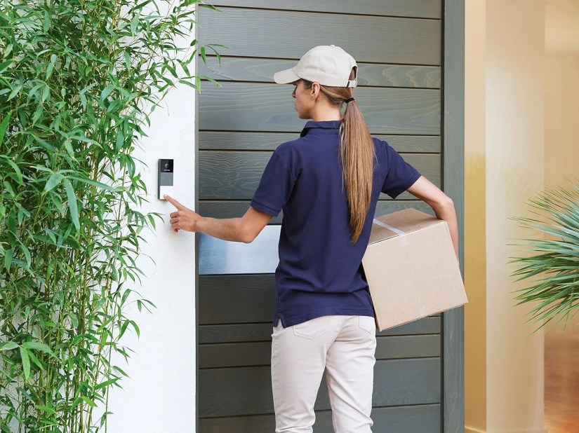 Delivery person ringing the doorbell with a package in her hand.