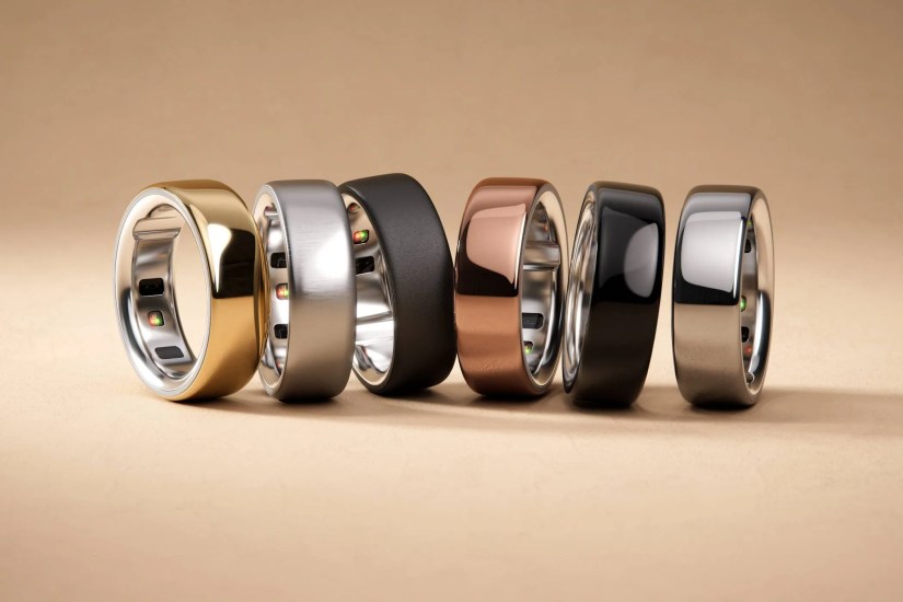 Oura Rings in a line, gold, silver black, copper, shiny black, and shinier silver from left to right