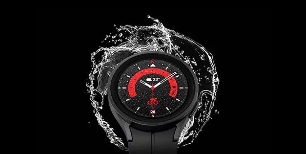 A Galaxy Watch with water splashing behind it on a black background.