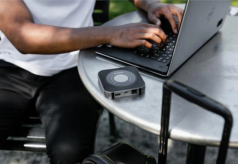 Nighthawk M1 4G LTE mobile router on cafe table with laptop.