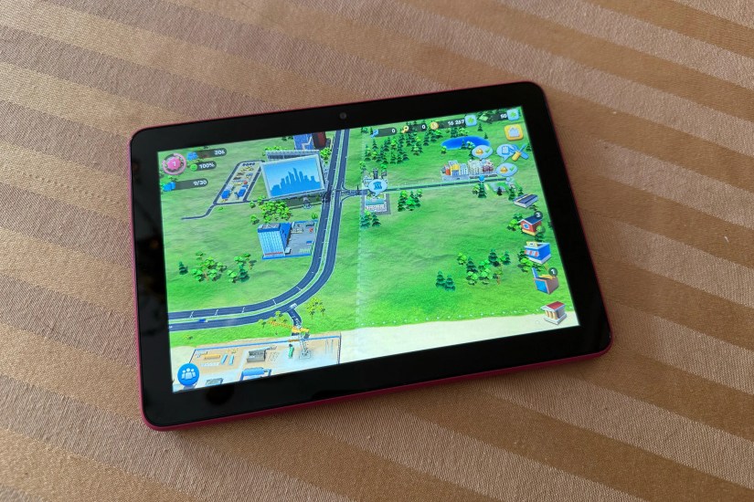 The Fire HD 8 showing Sim City running on it. Fire HD sits on a striped tablecloth.