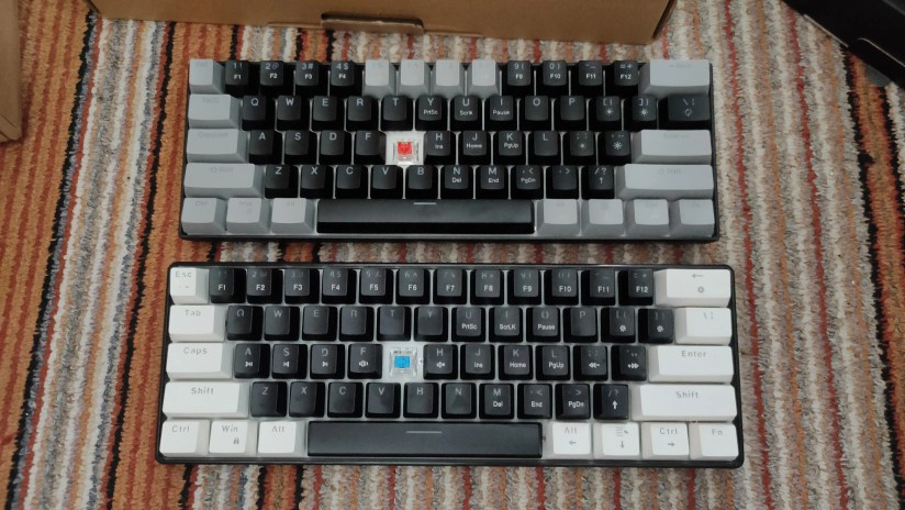 Two 60% mechanical keyboards with red and blue switches, with the G keycap removed.