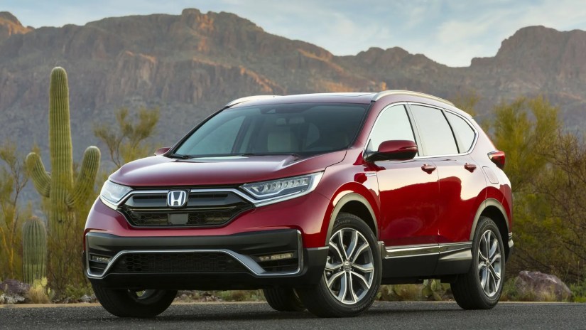 Full view of red 2020 Honda CR-V Hybrid parked on tarmac next to a catcus with mountains in the background.