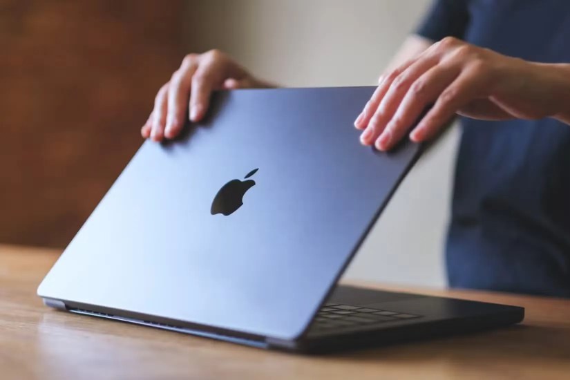A person opening a MacBook&rsquo;s lid.
