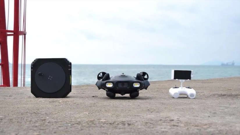 FIFISH by QYSEA Technology being displayed on a sandy beach with the sea in the background.
