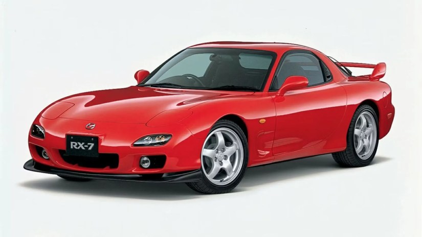 Front 3/4 view of a red 2001 Mazda RX-7 i a studio with a white background.