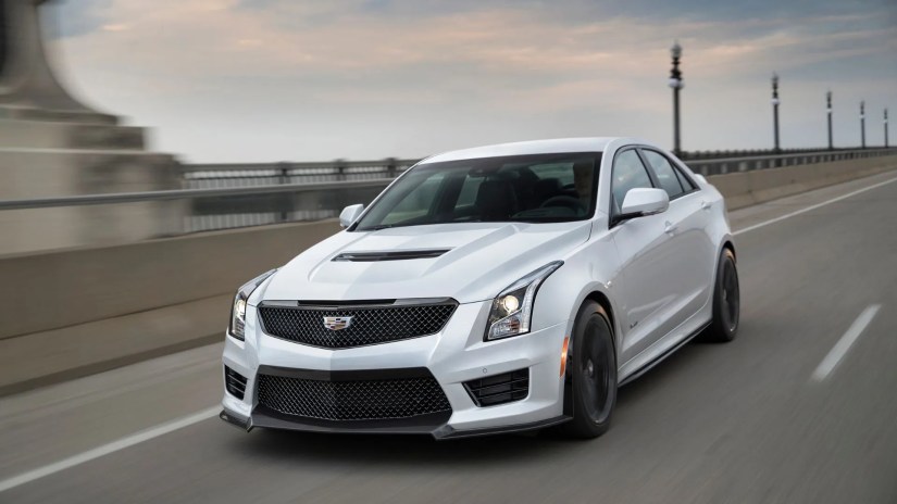 Front 3/4 view of a white 2018 Cadillac ATS-V Sedan driving on a freeway.