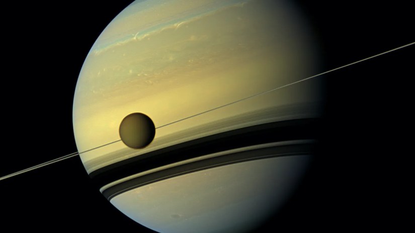 A view of Saturn with the large moon Titan visible in front of it.