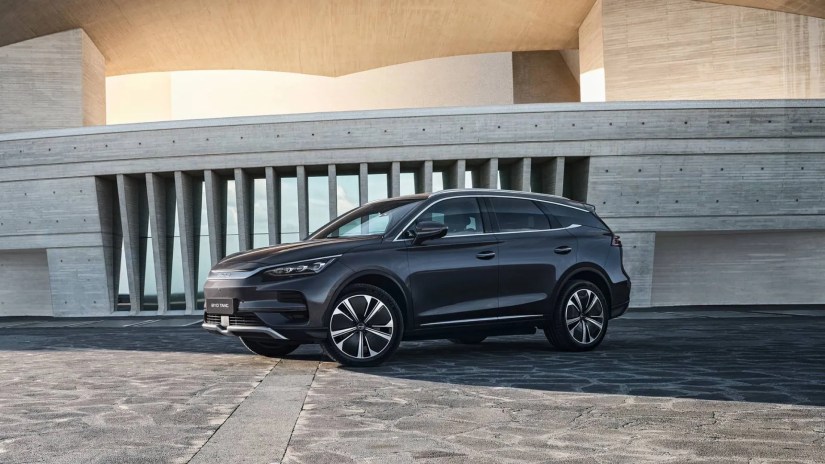 Friont three-quarter view of the BYD Tang parked next to some modern architecture.