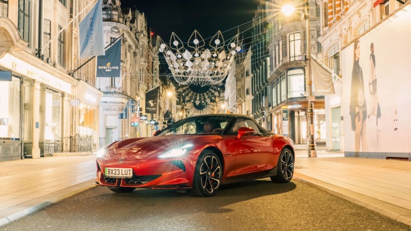 Front 3/4 view of a red MG Cyberster parked on a street at night.