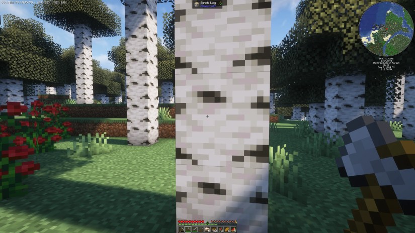 A birch tree in Minecraft with an axe in hand ready to cut it down.