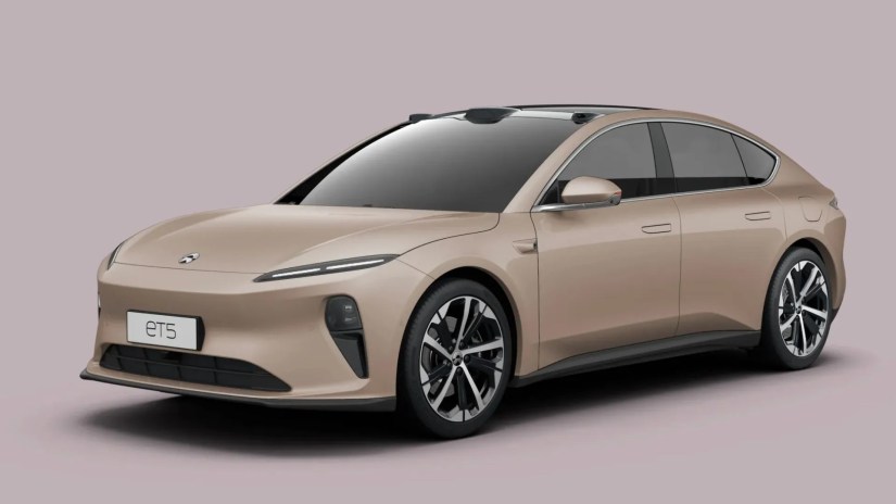 Front 3/4 view of a gold Nio ET5 Sedan in a studio with a pink backdrop.