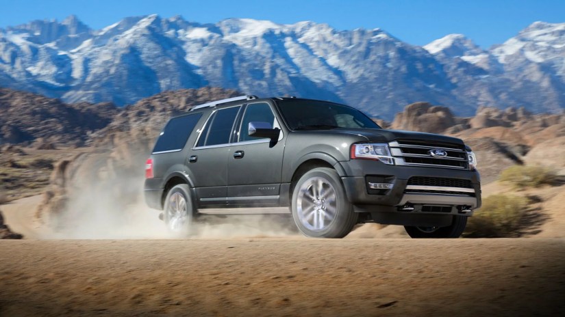 Front 3/4 shot of a gray 2017 Ford Expedition off-roading in sand with snow-capped mountains in the background.