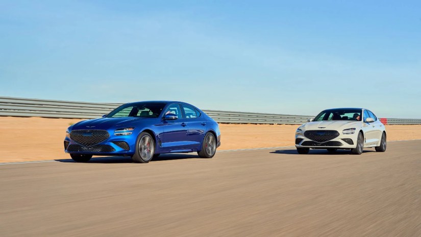 Front 3/4 shot of a blue and gray 2025 Genesis G70 driving on a freeway.