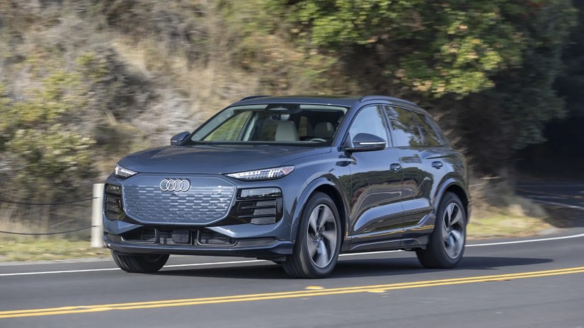 Front 3/4 view of a 2025 Audi Q6 e-tron driving on a country road.