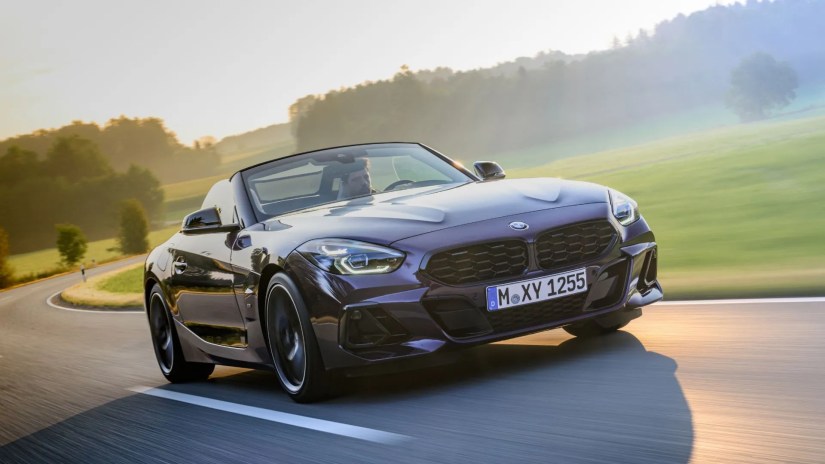 Front 3/4 shot of a purple 2023 BMW Z4 Roadster driving on a winding country road.
