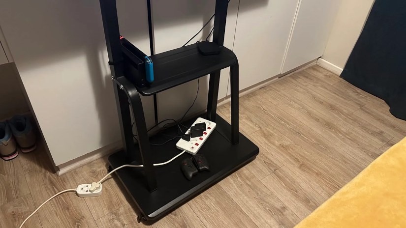 The bottom of a TV stand with a Switch dock and controller.