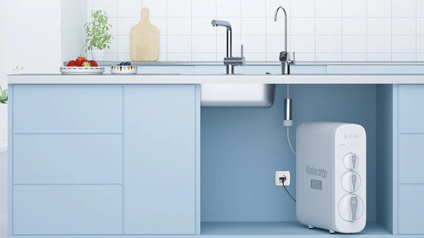 A water water filter sits below a sink in a blue kitchen