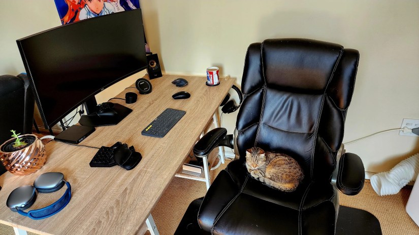 A desk with an ultrawide screen on it.