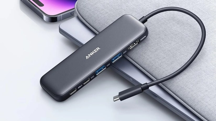 Anker&rsquo;s 332 5-in-1 USB-C hub sitting against a laptop shell with an iPhone in the background.