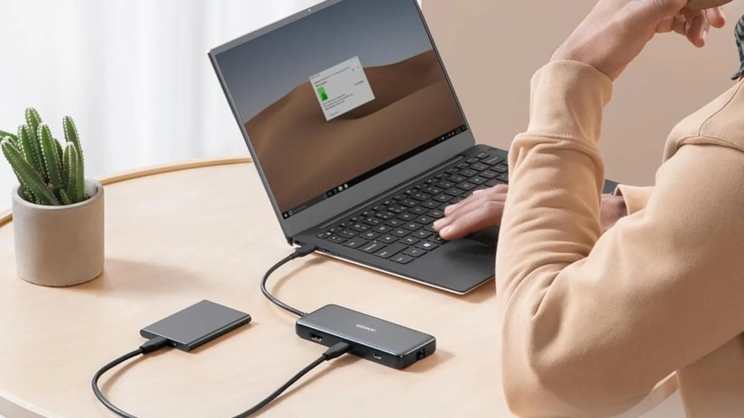 The Anker 555 8-in-1 USB-C hub sitting on a desk plugged into a laptop.