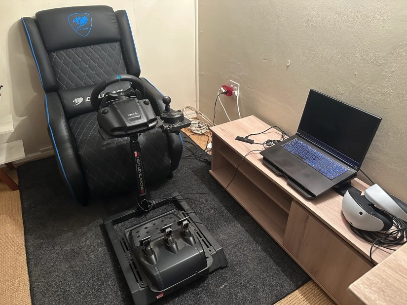 Laptop next to VR headset and racing setup.