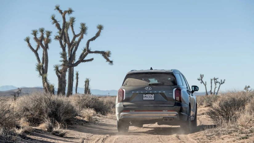 Dynamic rear shot of a gray 2025 Hyundai Palisade off-roading in the desert.