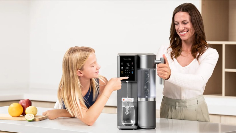 A woman and her daughter use a countertop water dispenser.