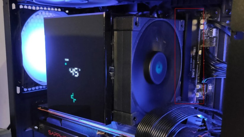 An air CPU cooler inside of a PC with a tightly fit RAM stick showing.