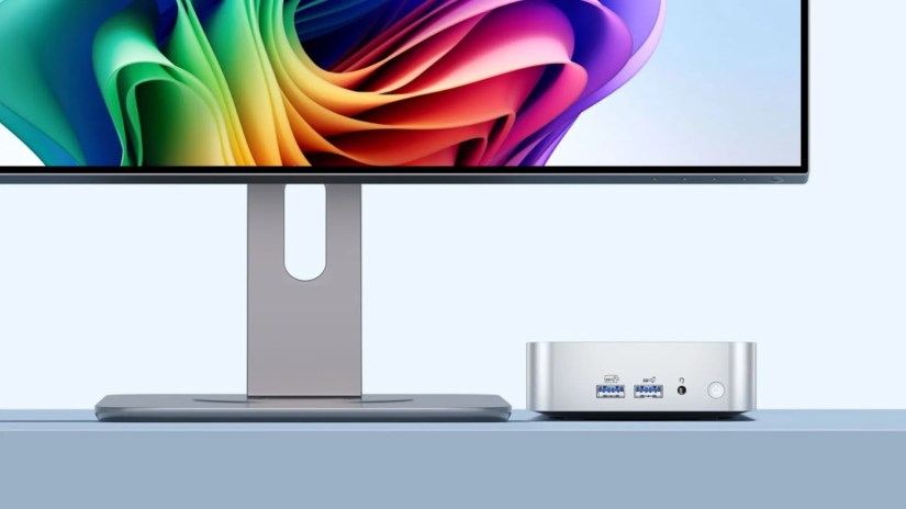 A GEEKOM A6 Mini PC sitting on a table connected to a monitor.
