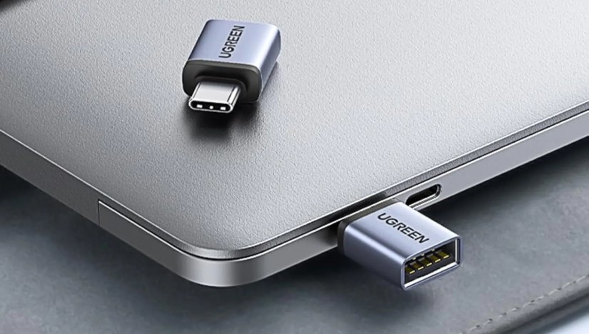 Two UGREEN USB-C to USB-A Adapters, one sitting on top of a laptop and one connected to said laptop.