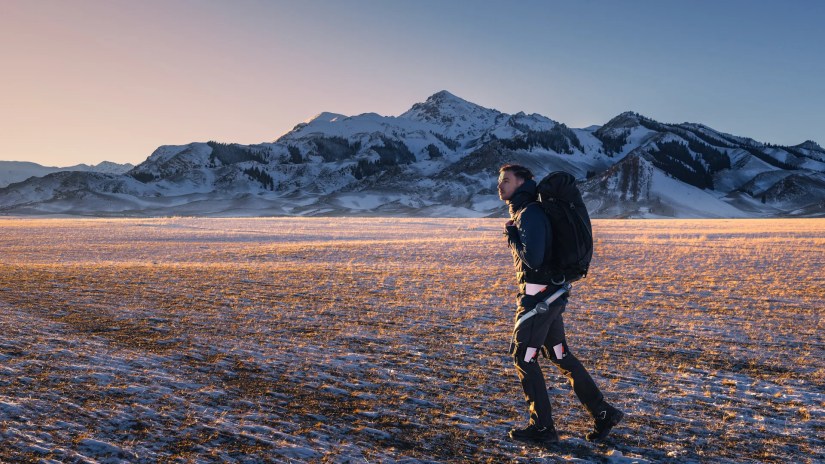 Hypershell X man with backpack looking at the sunset while hiking
