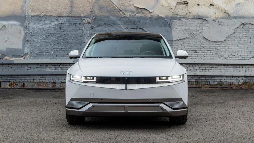 Static front-end shot of q hite 2023 Hyundai Ioniq 5 with a brickwall in the background.