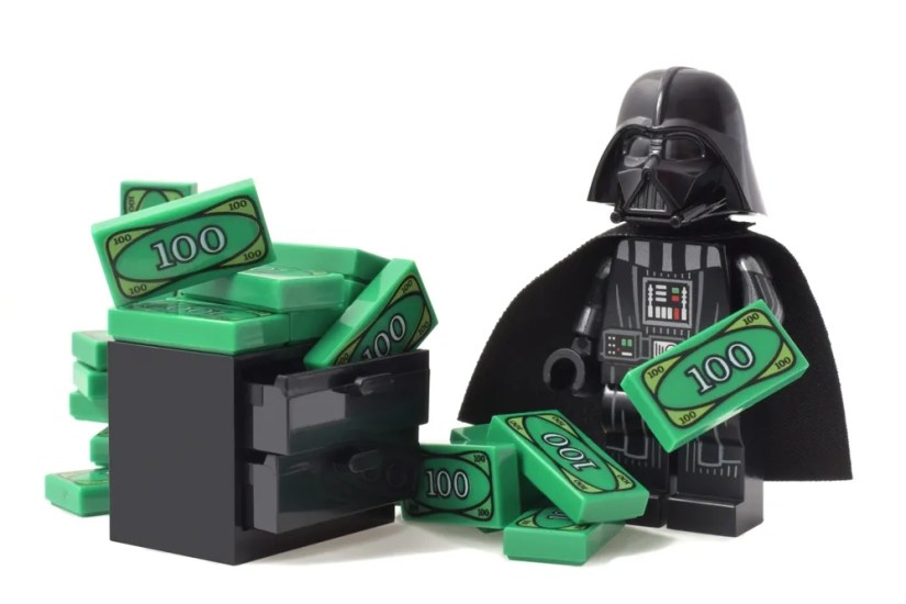 ego minifigure of Darth Vader or Star Wars is counting his money green banknotes.