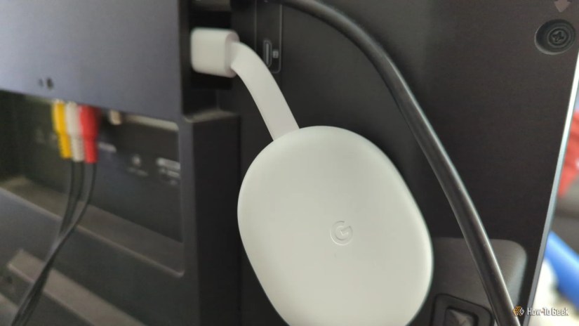 A Google Chromecast streaming device plugged into the back of a Roku TV.