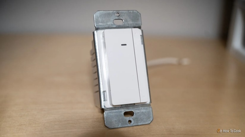 The Eve Dimmer Switch from the front sitting on a wooden shelf.