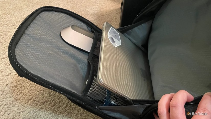 The Belkin Connect 11-in-1 USB-C Pro Dock in a backpack with a laptop and wireless earbuds.
