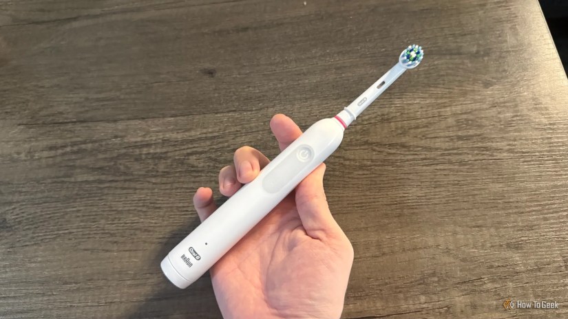 An Oral-B 1000 electric toothbrush held on a table.