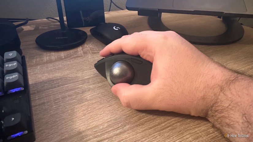 A hand holding the Logitech MX Ergo S.