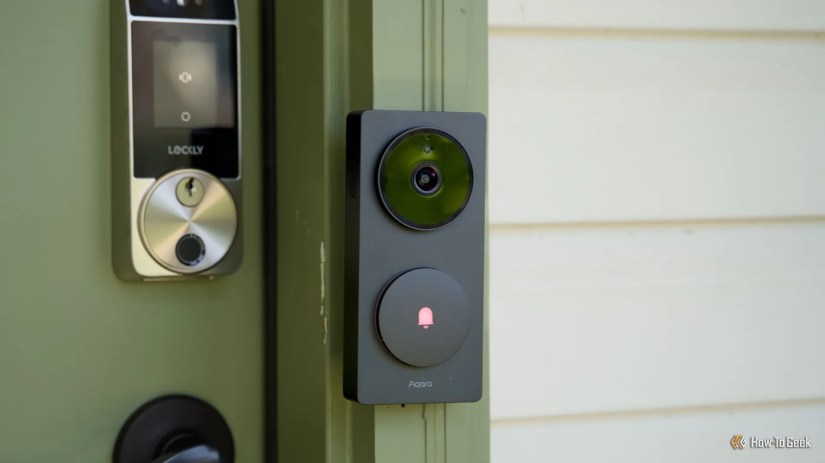 The Aqara Doorbell Hub G410 from the side mounted to a green door frame with a Lockly smart lock in the background.