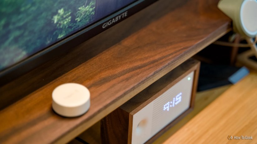 The top of a walnut desk shelf with an Awair 2nd Edition air quality monitor under it.